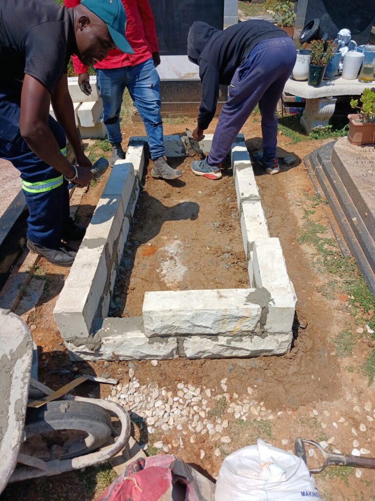 Professional tombstone installers from Mkhonto Tombstones preparing foundation at Fourways Memorial Park for Naidoo family memorial