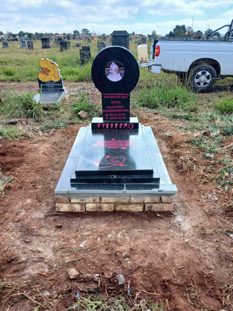 Black granite baby tombstone with pink engraving and facebrick foundation installed at South Park Cemetery Germiston