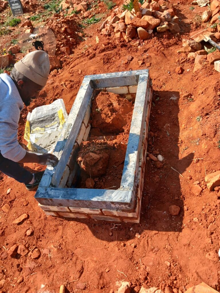 Completed child's memorial tombstone installation at Westpark Cemetery with brick foundation surround